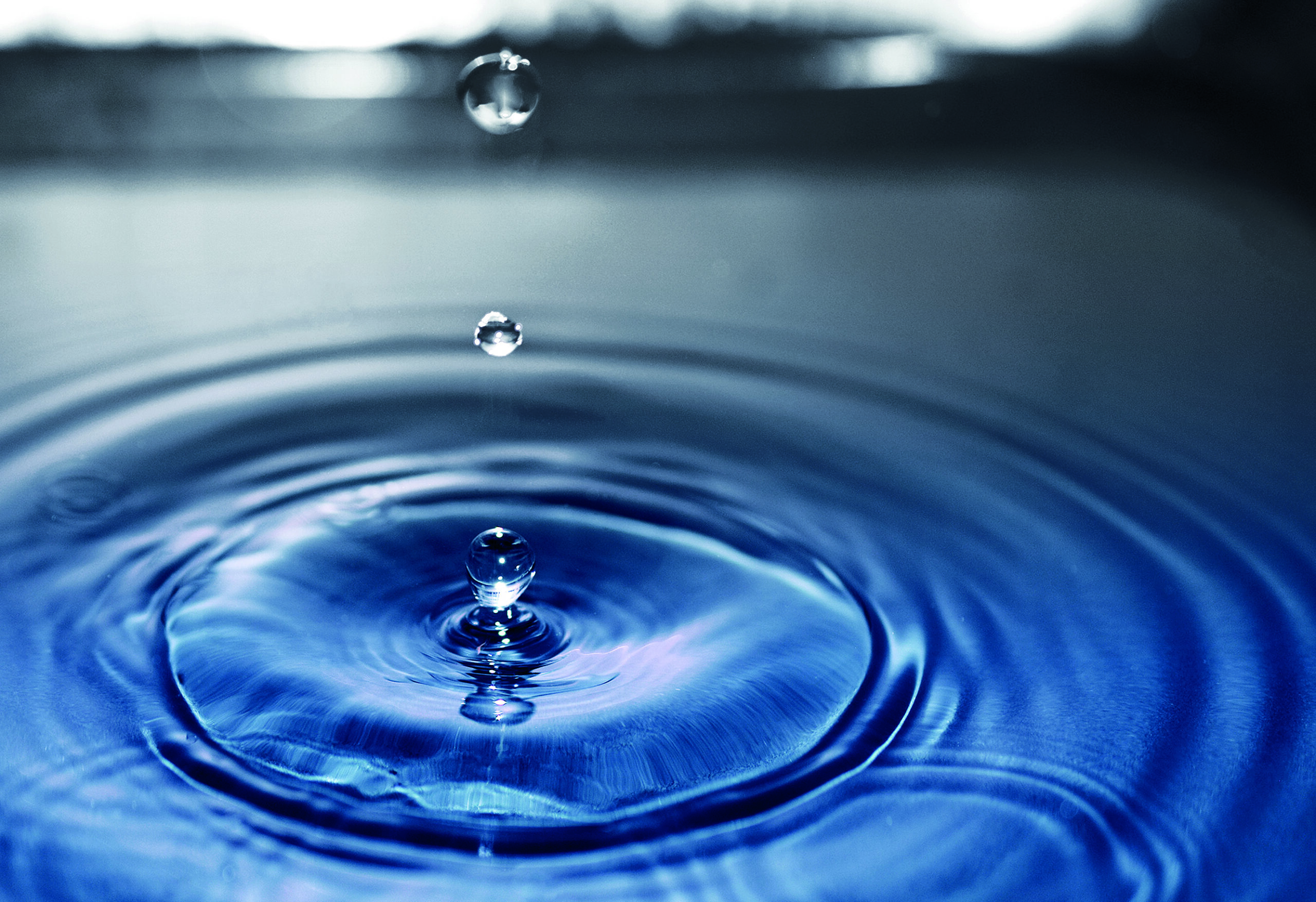 Macro close up impact of water drop splash on surface. Ripples,