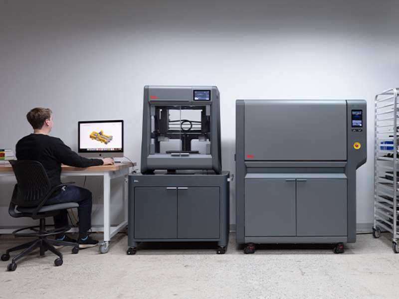 Desktop Metal Studio System 2 7 woman sits next to desktop metal shop system